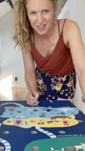 Amanda Rigby from Paper Rhino hand painting a kids game board co-produced with school children for Culture Leicestershire